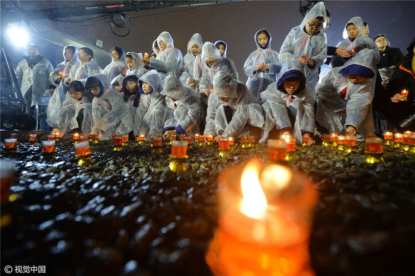 纪念馆祭奠广场内,手托红烛,低头默哀,为南京大屠杀死难者举行守灵暨