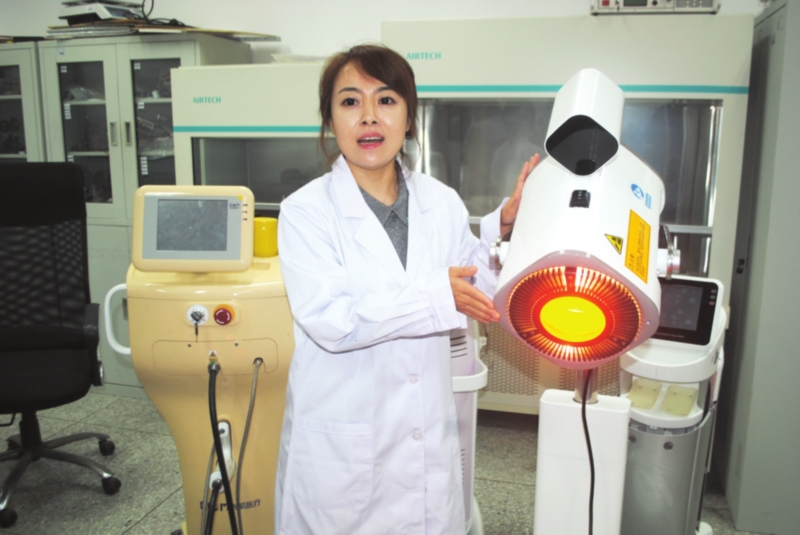 　　崔锦江博士向记者介绍“深层光谱治疗仪”。□记者　周建越　摄