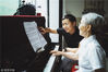 2018年6月29日，广东惠山，惠城区综合福利院的活动室里，钢琴教师梅晓钢正给满头银发的老奶奶上钢琴课，虽然年龄悬殊，但一个教得耐心，一个学得仔细。旁边还坐着三名学生——也都是年纪相仿的老人。王二/视觉中国