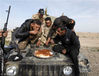 当地时间2014年12月8日，伊拉克Baiji郊区，伊拉克安全部队成员和什叶派武装人员坐在车头吃东西。