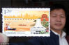 2018年10月18日，江苏苏州，一名集邮爱好者在邮政局展示刚购买的《广西壮族自治区成立60周年》纪念邮票。