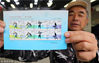2018年11月16日，一名集邮爱好者在江苏苏州邮政局展示刚购买的《北京2022年冬奥会——雪上运动》纪念邮票。