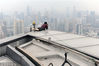 2013年06月22日，上海，高楼的一角，摄影师陆杰在拍摄。为了安全，他特地身绑一绳，拉住自己，以防不测。