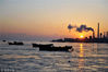 2018年2月6日，青岛胶州湾，初升的太阳映照海面上的海冰和渔船。