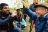 2018年3月10日，江苏镇江，外国留学生与社区志愿者为小树挂上护绿牌。