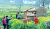2018年3月15日，江西省婺源县溪头乡江岭村，游客正在开心拍摄独具农家文化的花田稻草屋、稻草人，并与其合影留念。