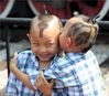 2011年9月11日，北京，一对双胞胎在街头玩耍，他们的妈妈给哥俩剃了葫芦兄弟“金刚葫芦娃”头，头顶是葫芦，两侧是葫芦叶。双胞胎在说悄悄话。