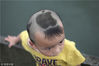 2012年6月23日，杭州，西湖断桥上，一名小男孩的发型很有趣，头顶是咬了一口的苹果图案。
