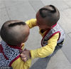 2012年10月2日，北京第九届北京双胞胎文化节上，一对可爱的双胞胎兄弟头上分别剃有“1 ”和“2”两个数字，在一起玩耍