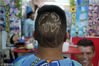 当地时间2014年7月7日，玻利维亚拉巴斯，一个球迷用手机展示2014世界杯标志，让理发师为他剪出同样的发型。