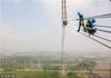 2018年4月15日，安徽芜湖，在无为县高沟镇群英村，安徽送变电工程有限公司施工人员在210米高空安装特高压跨越塔导线附件。