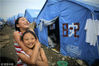2008年6月7日，四川绵竹，距离“5·12”大地震已将近一周，两个幸存的小女孩已经重新开始了她们的生活。她们身后是安置灾民的临时帐篷。ChinaFotoPress