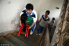 2012年6月22日，广东惠州，无力行走的陈斌，每次上下楼梯都需要妈妈来背，准备好的凳子可以在妈妈累时乘坐休息。视觉中国