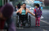 2018年3月8日，贵阳，走下坡路时，姐姐田梦秋紧紧拉着姨妈谢修梅的手，而李梦媛则继续把握着轮椅把手前行。
洋马儿/视觉中国