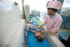 2018年5月13日，在江苏省泰州市人民医院南院新生儿重症监护室（NICU），“临时妈妈”房京丽在给新生儿沐浴。