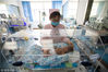 2018年5月13日，在江苏省泰州市人民医院南院新生儿重症监护室（NICU），“临时妈妈”王蔚在整理管道，防止压到宝宝娇嫩的皮肤。
