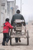 2010年1月2日，河南省安阳市汤阴县菜园镇，一名小学生帮着父亲推一辆载着重物的木板车，为父亲减负。常中正/视觉中国