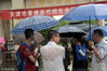 2018年6月7日早晨，2018年高考拉开帷幕。天津遭遇短时阵雨，考生冒雨进入考场。一名父亲将自己的伞给了孩子，自己全身被淋湿，衬衫贴在身上。游思行 腾讯大燕网/视觉中国
