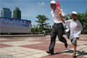 2008年6月15日，海南海口，一位父亲带着儿子共持模拟火炬参加“亲情接力”赛跑。当天，海口市在万绿园举办了一场“感恩父爱 亲情接力”公益活动。