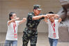 2018年7月11日，江苏连云港市革命纪念馆，连云港公安边防支队官兵为参加连云港市组织的“红色之旅”夏令营的小学生们纠正军事动作。