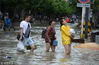 2018年7月12日，成都金堂县，群众经过积水的街道。市民不受洪水影响，保持愉快心情，以笑容面对。