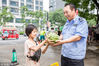 7月14日上午，来自宜阳县高村乡宋屋村的10岁“小瓜农”康康的摊位前迎来了一个大主顾，一次性买下一整车西瓜，可把康康乐坏了。
图为康康送瓜给帮助他的门卫大爷。
