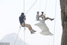 2013年10月26日，广西柳州，方静穿着婚纱，和先生挂在空中拍摄婚纱照。摄影师也吊在空中拍摄。