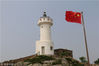 2018年8月14日，江苏省连云港市灌云开山岛民兵哨所。国旗在灯塔映衬下鲜艳夺目。
