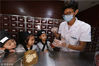 2018年8月17日，在江苏淮安盱眙县中医院，中药师在指导孩子学习中药材配置方法。