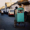 1991年，北京，一个男人骑着自制的三轮厢车，送孩子上学。