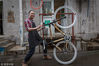 2017年8月，北京。在北京的一个老胡同里，一个叫David的歪果仁，和小伙伴共同经营着一间叫做BBB（Bamboo Bicycles Beijing）的竹子自行车工作坊。在这里，大家一起动手，从竹子车架开始，经过打磨、紧固、装饰，做着这个城市里独一无二的竹子自行车。2017年8月底的一个雨后，北京郞家胡同，这位穿着格子衬衣的BBB指导老师，双手擎起刚做好的自行车骄傲地向人展示。詹敏/视觉中国