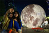 2018年9月23日，市民在南京街头布置的超级“月亮”景观球前留影。