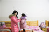 2019年1月9日，在贵州毕节市大方县儿童福利院内，卢小卜正在给孩子穿衣。