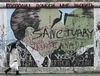 当地时间2001年12月9日，德国柏林，图为在柏林墙1.3公里长的“东侧画廊”，一名女子走过苏联领导人列昂尼德·勃列日涅夫(左)和东德领导人埃里希·昂纳克之间著名的亲吻画面。JOHN MACDOUGALL /视觉中国