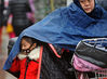 2016年11月22日，武汉街头，一位小女孩从挡风御寒的雨衣中钻出，准备步入校园。苗剑/视觉中国