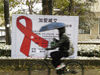 2015年11月22日，北京，清华大学，骑车大学生从加爱减艾滋病宣传红丝带广告前经过。阿青/视觉中国