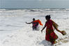当地时间2019年11月29日，印度金奈，几个孩子在白色污染物泡沫与海浪混合的海滩玩耍。