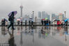 2019年2月18日，上海，细雨绵绵，在中山东一路景观平台上，不少游客在雨中打伞游览外滩，对岸的陆家嘴高楼大厦在雨雾中若隐若现。王冈/视觉中国