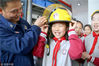 2019年3月25日，江苏省苏州市平江新城实验小学的学生在消防员的指导下体验戴消防帽。