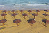 2019年5月22日傍晚，山东青岛西海岸新区黄海之滨的海滩上，供人们夏日亲海戏水使用的木伞，犹如一朵朵伞花绽放在金色的海滩和洁白的海浪边。