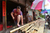 2019年5月23日，成都，双流区彭镇街道修伞手艺人杨敏在用锯子锯伞架材料。