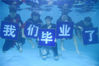 2019年6月22日，杭州浪浪浪水公园，毕业生们身着学士服、手托学士帽潜入水底，摆出各类创意造型，在水下定格青春回忆。