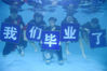 2019年6月22日，杭州浪浪浪水公园，毕业生们身着学士服、手托学士帽潜入水底，摆出各类创意造型，在水下定格青春回忆。连国庆/视觉中国