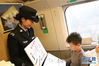 　1月10日，钱程手拿漫画，为旅客讲解铁路安全知识。新华社发（范玉朋 摄）