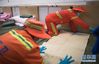 2月12日，在武汉体育中心方舱医院，工人在病床上铺设电热毯。 当日，武汉体育中心方舱医院具备收治条件，这里将提供1100张医疗床位，收治新冠肺炎轻症患者。 新华社记者 肖艺九 摄