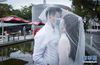2月14日，完成结婚登记的张铃雯（右）和黄苗炜在深圳市南山区民政局婚姻登记处前留影。 新华社记者毛思倩摄