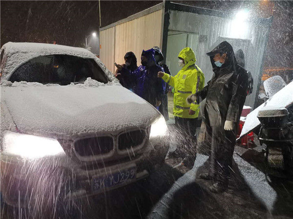 大雪纷飞 他们坚守一线卡口为进出车辆人员测体温