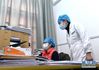 染病康复后第一天上班的护士蔡桃英（右）来到医院人事部门查看自己返岗后的任务（2月22日摄）。新华社记者 李贺 摄