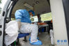 　2月7日，在进入确诊病例密切接触者居家隔离户前，黄文科在救护车上穿戴防护器具。新华社记者 刘潺 摄
