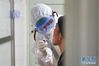 易俊丰（左）在湖南省人民医院发热门诊接诊区取咽拭子标本（2月7日摄）。 新华社记者 陈泽国 摄